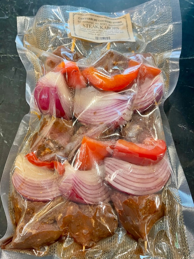 Vacuum-sealed package of steak kabobs with pieces of marinated beef, red bell peppers, and red onions, labeled as 'Canterbury Country Store all natural, no MSG, marinated steak kabobs.'