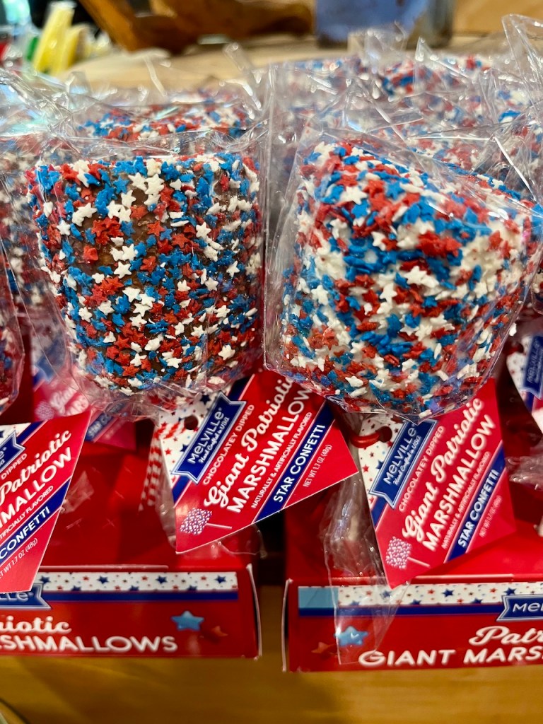 Packaging of giant patriotic marshmallows decorated with red, white, and blue star-shaped confetti, displayed on a store shelf.