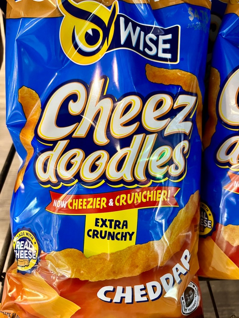 A close-up of a bag of Wise Cheez Doodles, featuring the flavor 'Cheddar' with a label that states 'Extra Crunchy'.