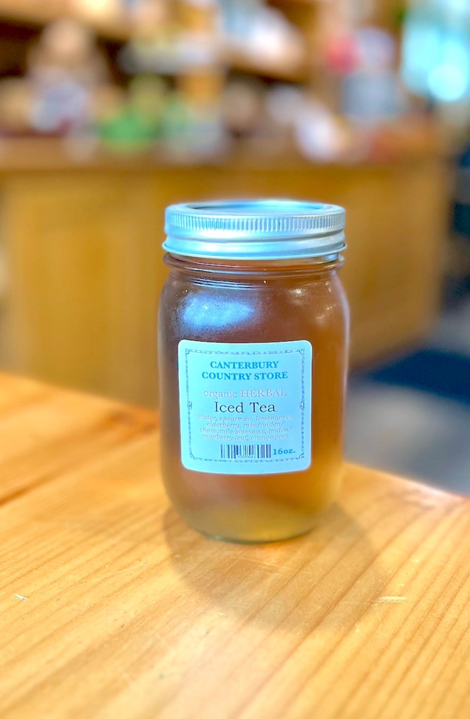 A jar of organic herbal iced tea from Canterbury Country Store, displayed on a wooden table.