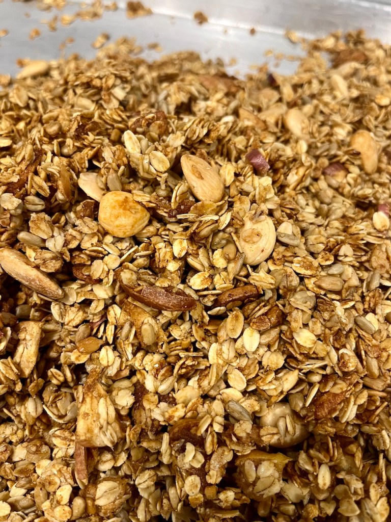 Close-up of homemade organic granola, featuring oats, nuts, and a golden brown color with visible texture.