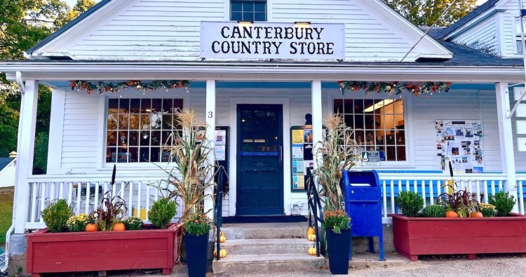 Front view of the Canterbury Country Store, featuring a welcoming entrance with seasonal decorations, planters, and a blue mailbox.