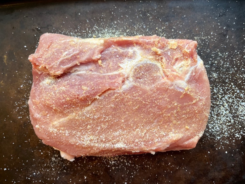 A seasoned pork loin roast placed on a baking tray, ready for cooking.