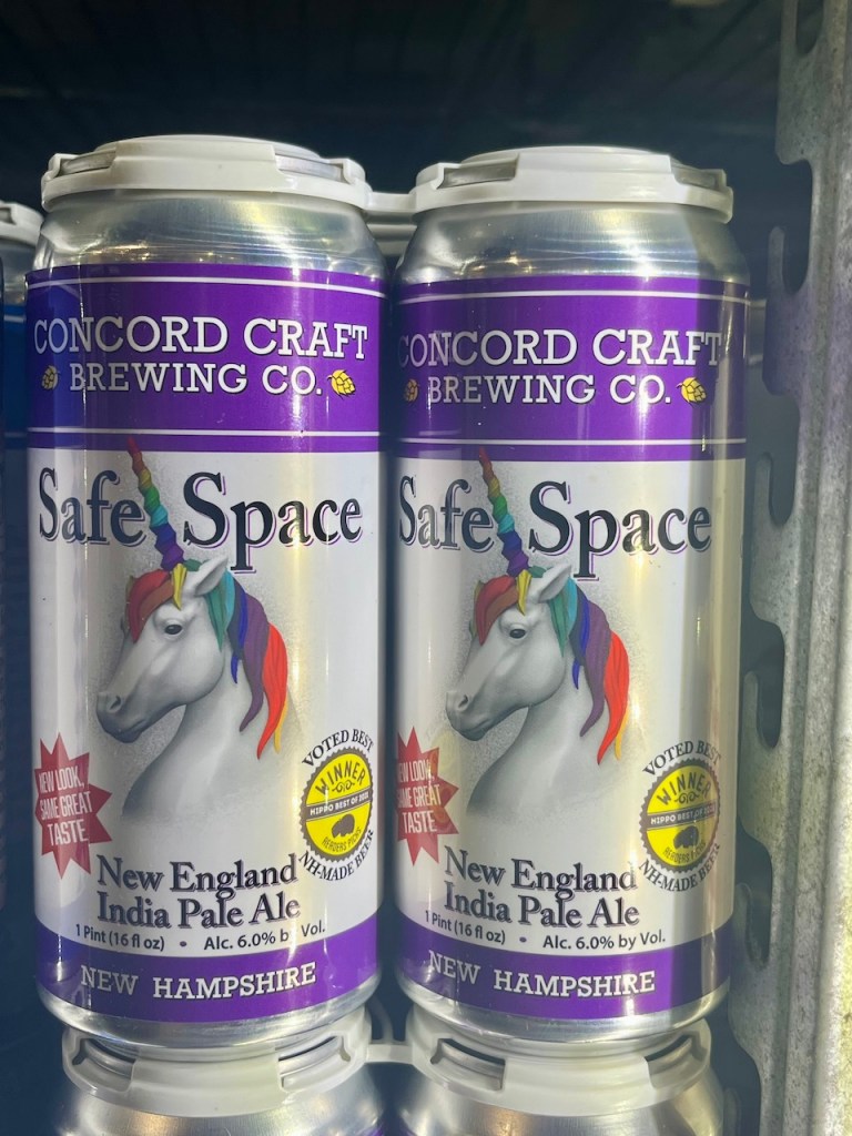 Two cans of Concord Craft Brewing Co.'s 'Safe Space' New England India Pale Ale featuring a unicorn design, placed on a shelf.