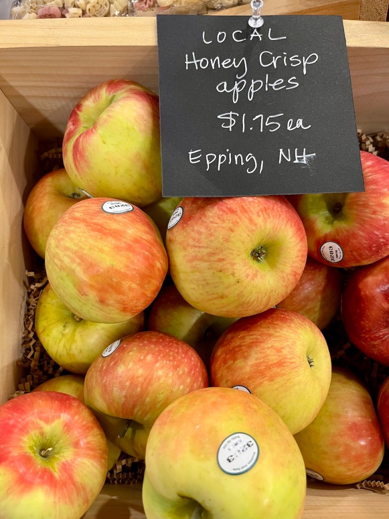 A basket filled with local Honey Crisp apples, with a price tag reading $1.75 each, from Epping, NH.