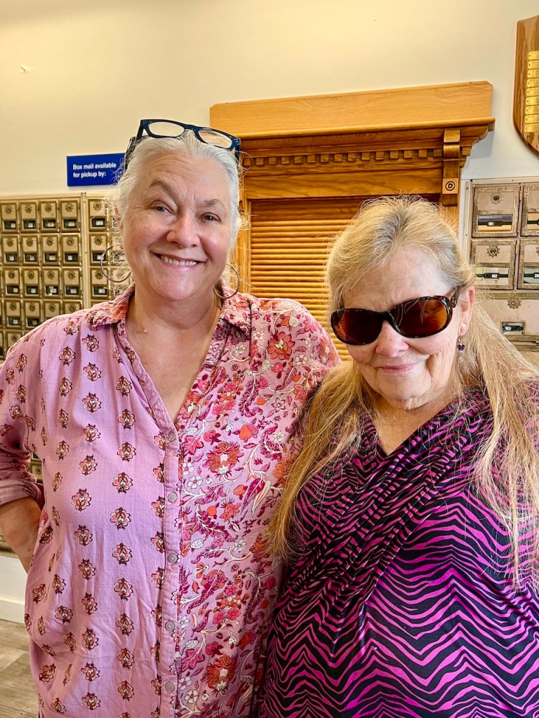 Two women smiling together inside a country store, showcasing a friendly atmosphere.