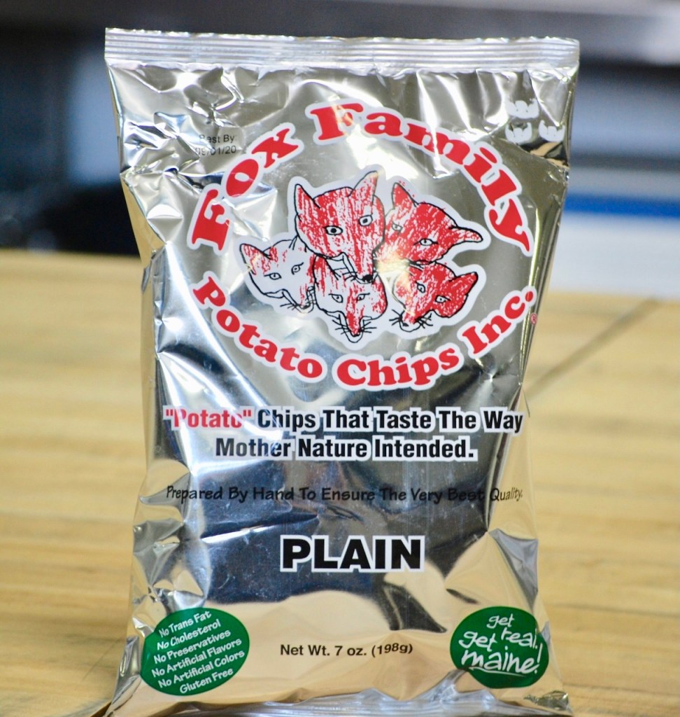 Silver bag of Fox Family Potato Chips labeled 'Plain', featuring artwork of red foxes and text about the natural quality of the chips.