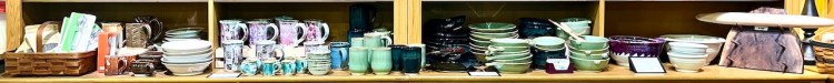 A display of various kitchenware including bowls, plates, cups, and utensils arranged on shelves.